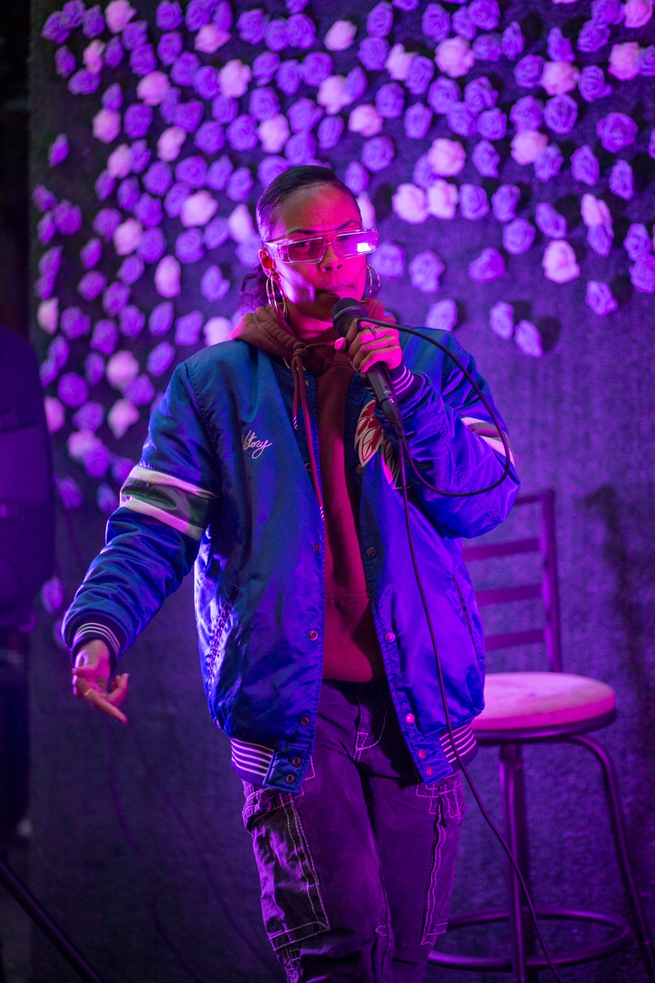Poet performing in a blue jacket at Hues Cookout 2022